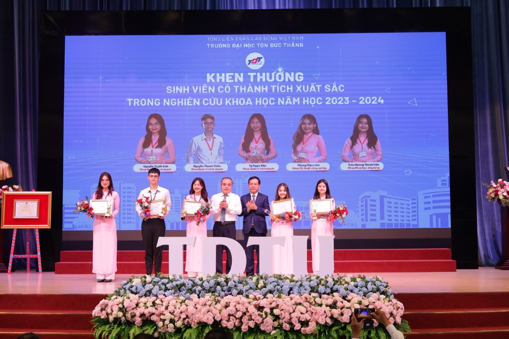 Mr. Tran Hoang Tuan, Permanent Vice Chairman of the Quang Ngai Provincial People's Committee, and Dr. Vu Anh Duc, Secretary of the Party Committee and Chairman of the University Council, presenting awards to students for their outstanding achievements in scientific research